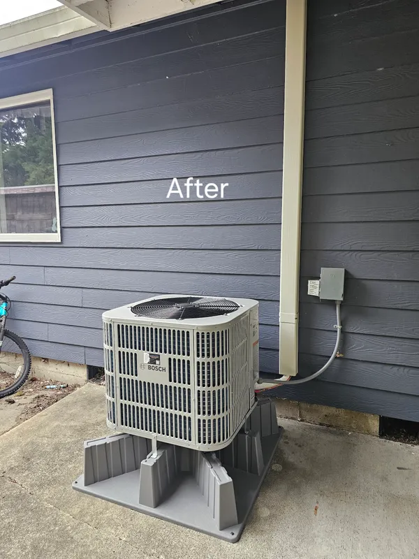 Bosch heat pump installed against navy siding — completed installation
